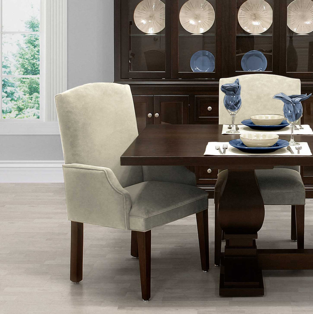 Cream upholstered dining arm chair with rolled arms and dark tapered legs at a pedestal dining table