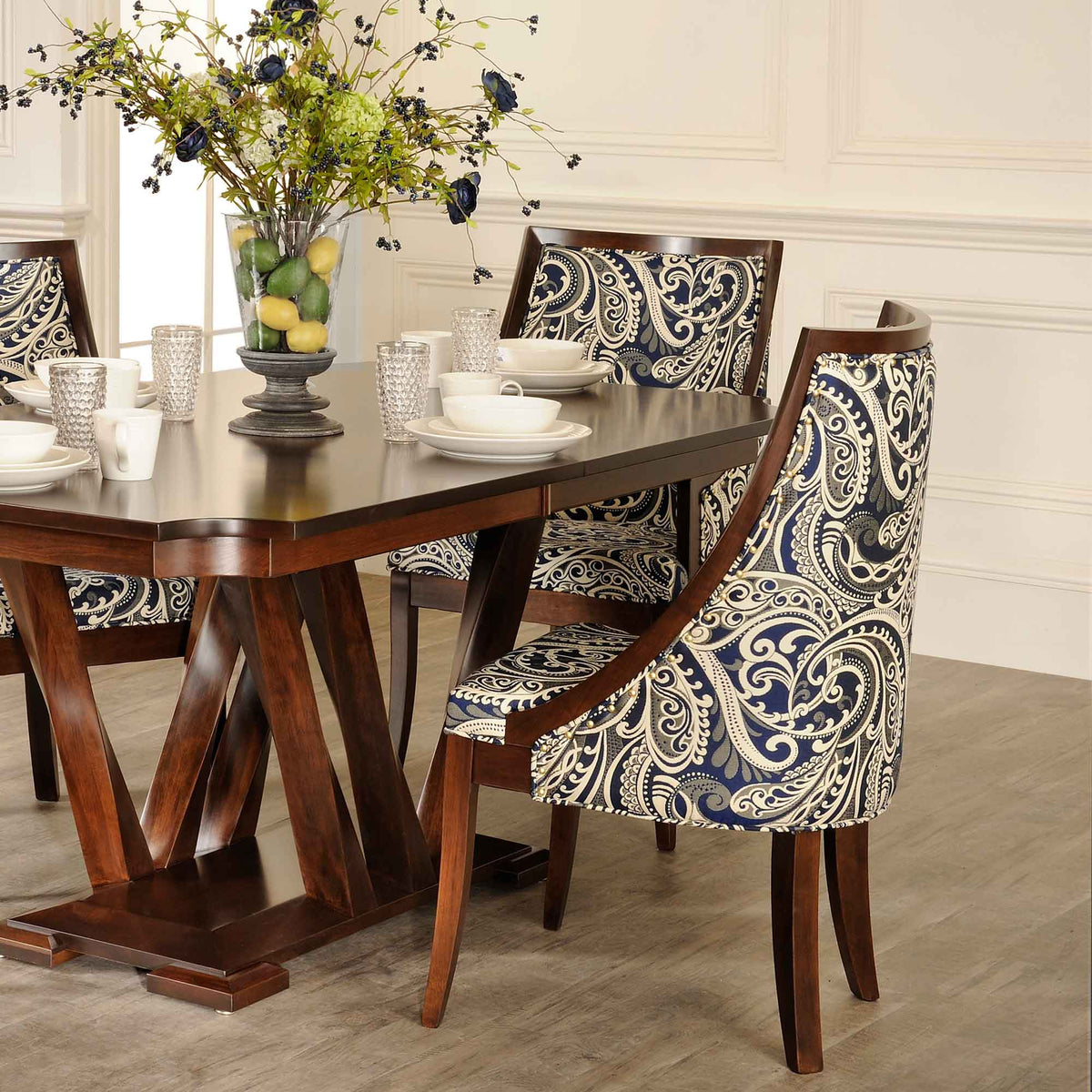 Dining room set with Park Ave paisley cushion chairs around a dark trestle table styled with white dishes and a floral arrangement