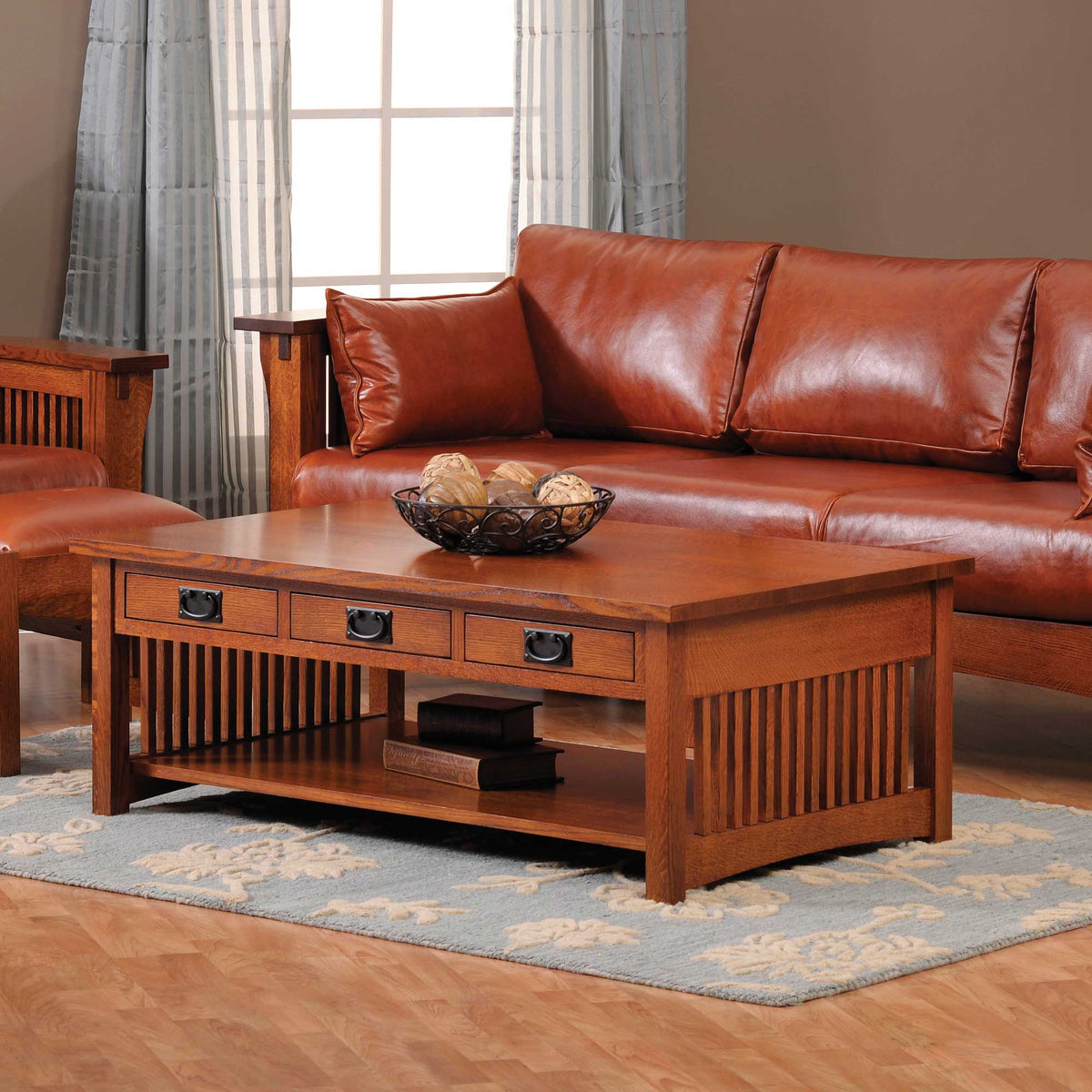A rectangular brown wooden coffee table with storage drawers and lower shelf, placed on a blue patterned rug, with a brown leather sofa in the background.