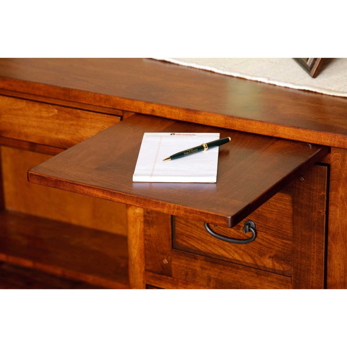 Pull out writing slide extended from a cherry desk with a notepad and pen resting on the surface
