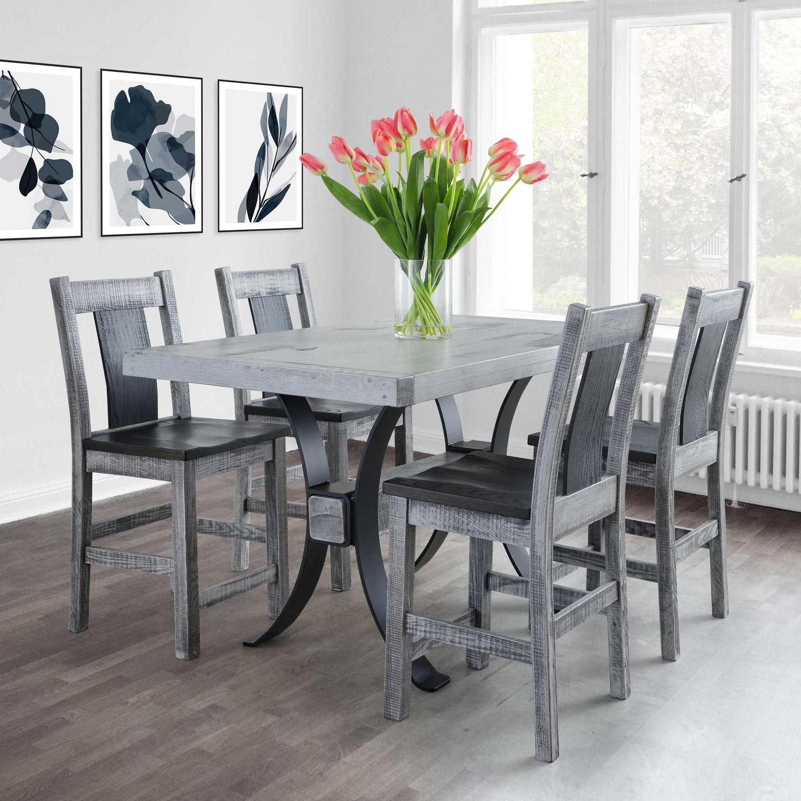 Weathered gray counter height table with four matching stools and dark seats in a bright dining room with tulips