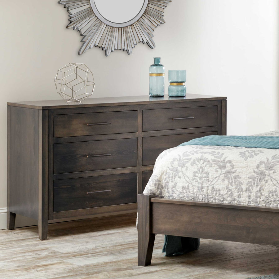 Gray stained six drawer dresser with bronze bar pulls beside a matching sleigh bed under a silver sunburst mirror