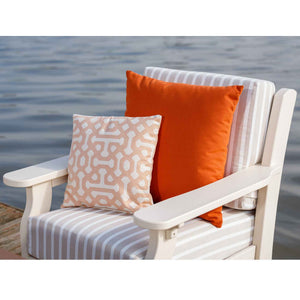 White poly patio chair with gray striped cushions and orange and blush pillows on a dock overlooking the water