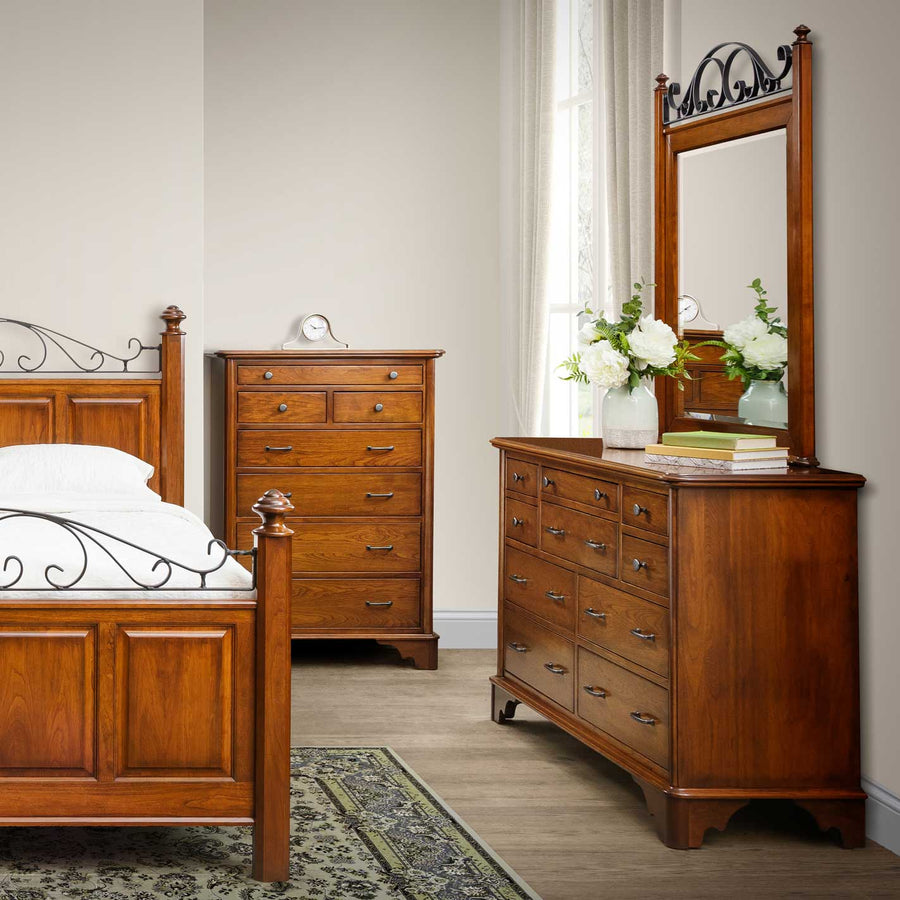 Cherry chest of drawers and a dresser with iron scroll mirror beside a matching scrollwork bed