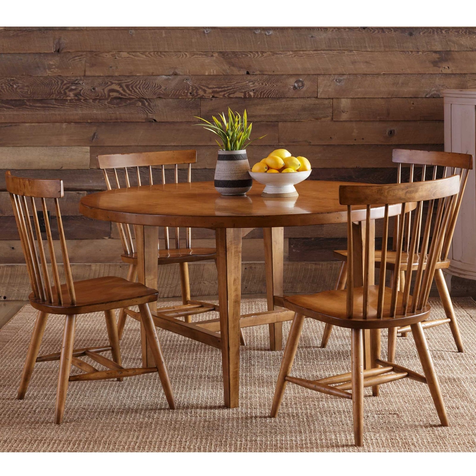 Round trestle dining table in warm maple with an aged plank top and angled legs joined by a center stretcher