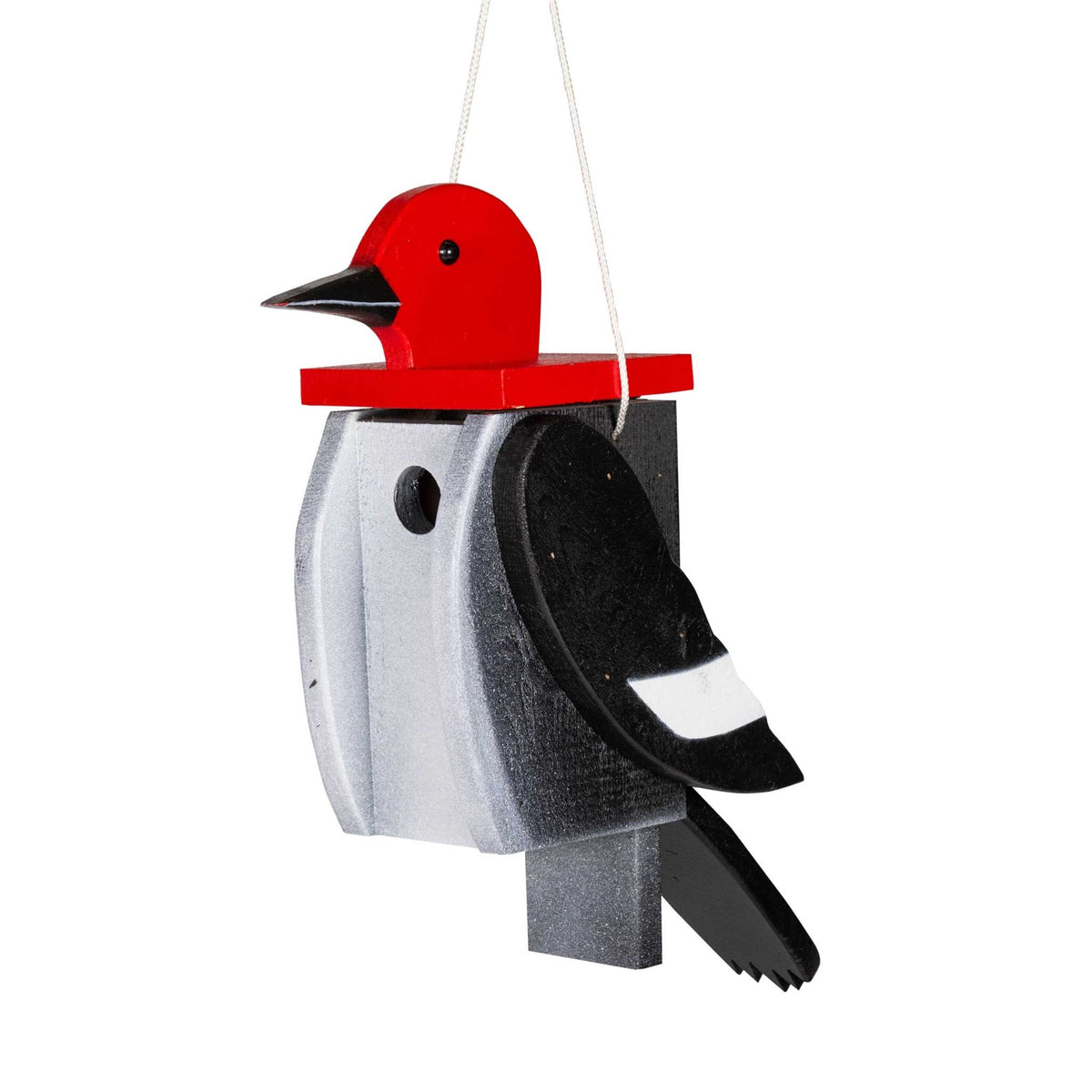 Hanging wooden woodpecker birdhouse with red painted head, black tail and wing, round entry hole and rope hanger on a white background