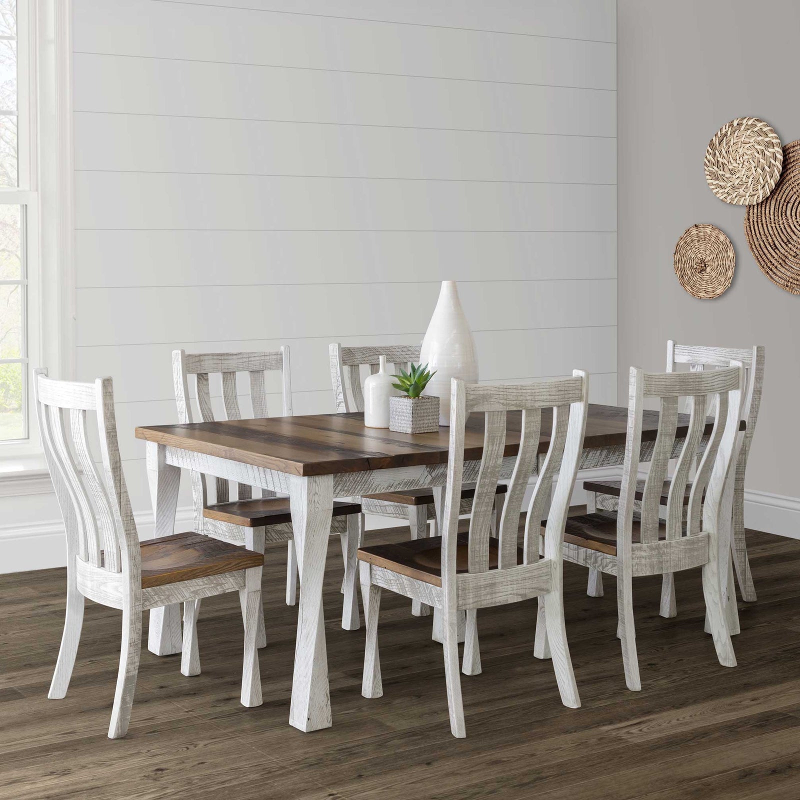 Whitewashed rustic dining set with a warm brown plank top table and six curved slat back chairs in a shiplap dining room