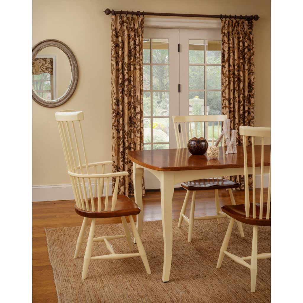 Cream painted leg table with a cherry top and buttercream Windsor chairs with stained seats in a sunny dining room