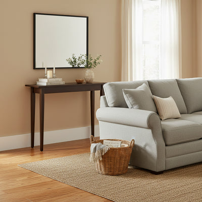 Slim dark walnut Shaker console table styled against a beige wall with mirror, candles and greenery beside a light gray sofa