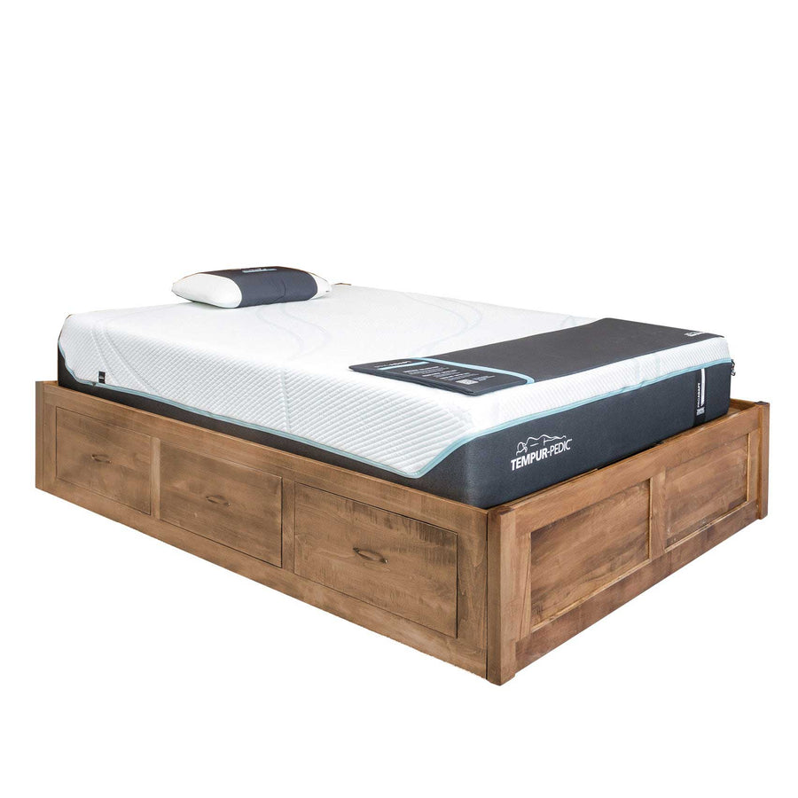 Rustic wood captain storage bed base with three side drawers and paneled ends, topped with a foam mattress