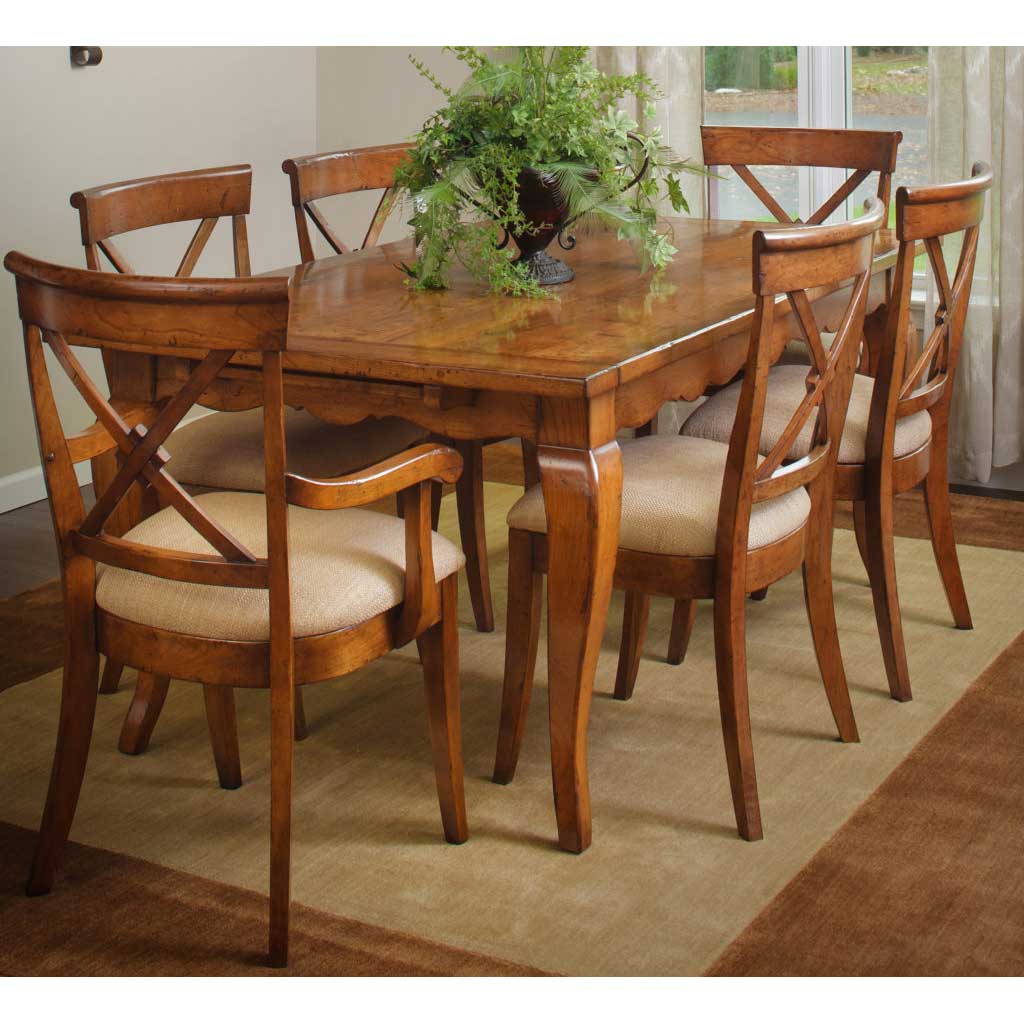 Farmhouse dining set with a rectangular wood table and six X-back chairs with cream upholstered seats on a wool rug