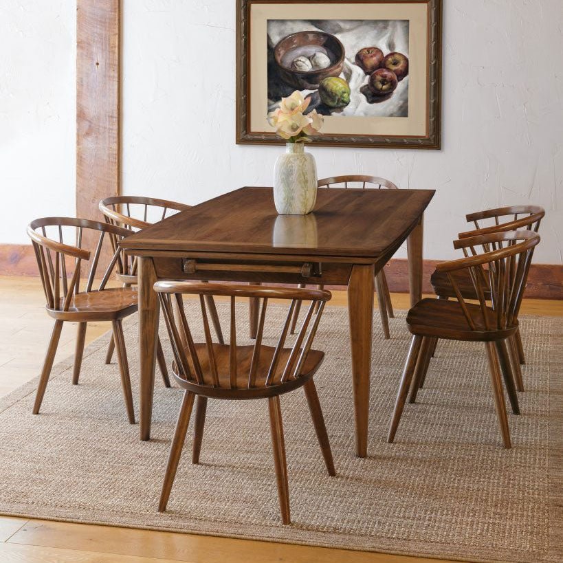 Mid-century modern walnut dining set with a draw leaf table and six curved spindle back chairs on a jute rug