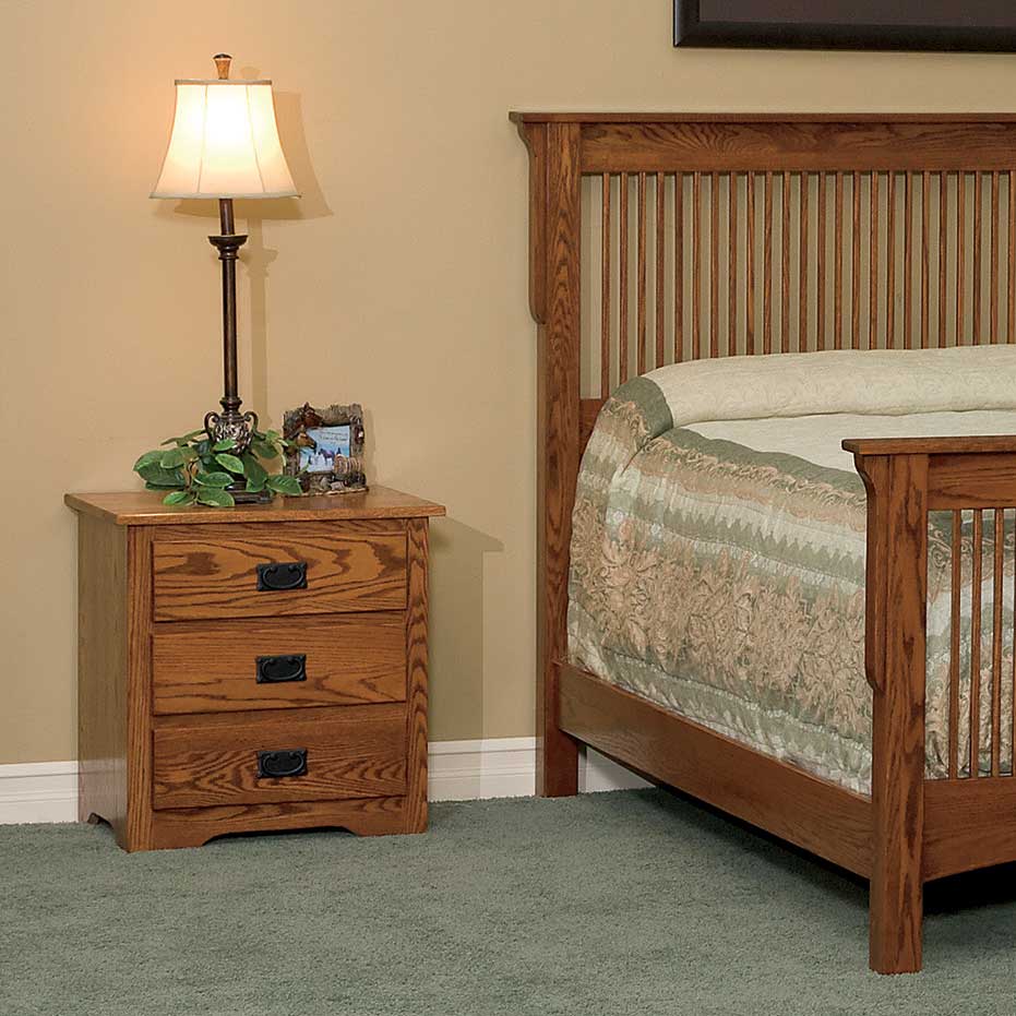 Oak three drawer Mission nightstand with a lamp beside a slatted Mission bed in a tan bedroom