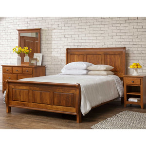 Cherry sleigh bed with raised panel headboard and footboard, styled with white bedding beside a dresser and nightstand