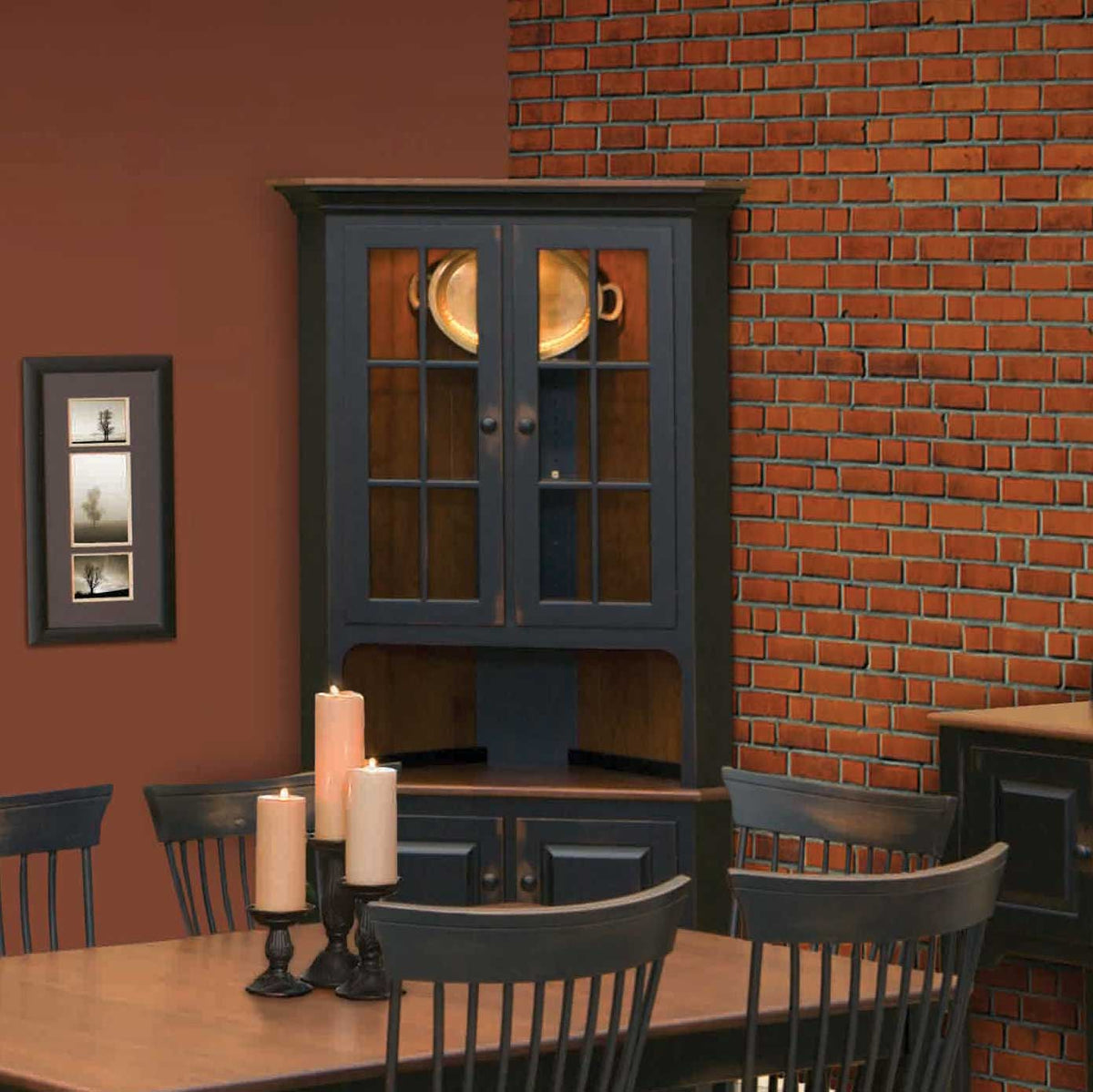 Black corner hutch with lit glass doors holding a brass tray and white plates, shown in a brick dining room