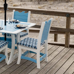 White and blue wave back poly dining chairs with navy ikat seat cushions at a table on a beach deck