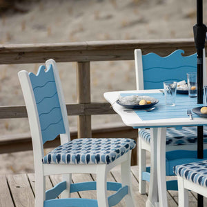Blue and white wave crest dining chairs with patterned ikat cushions around an umbrella table by the dunes
