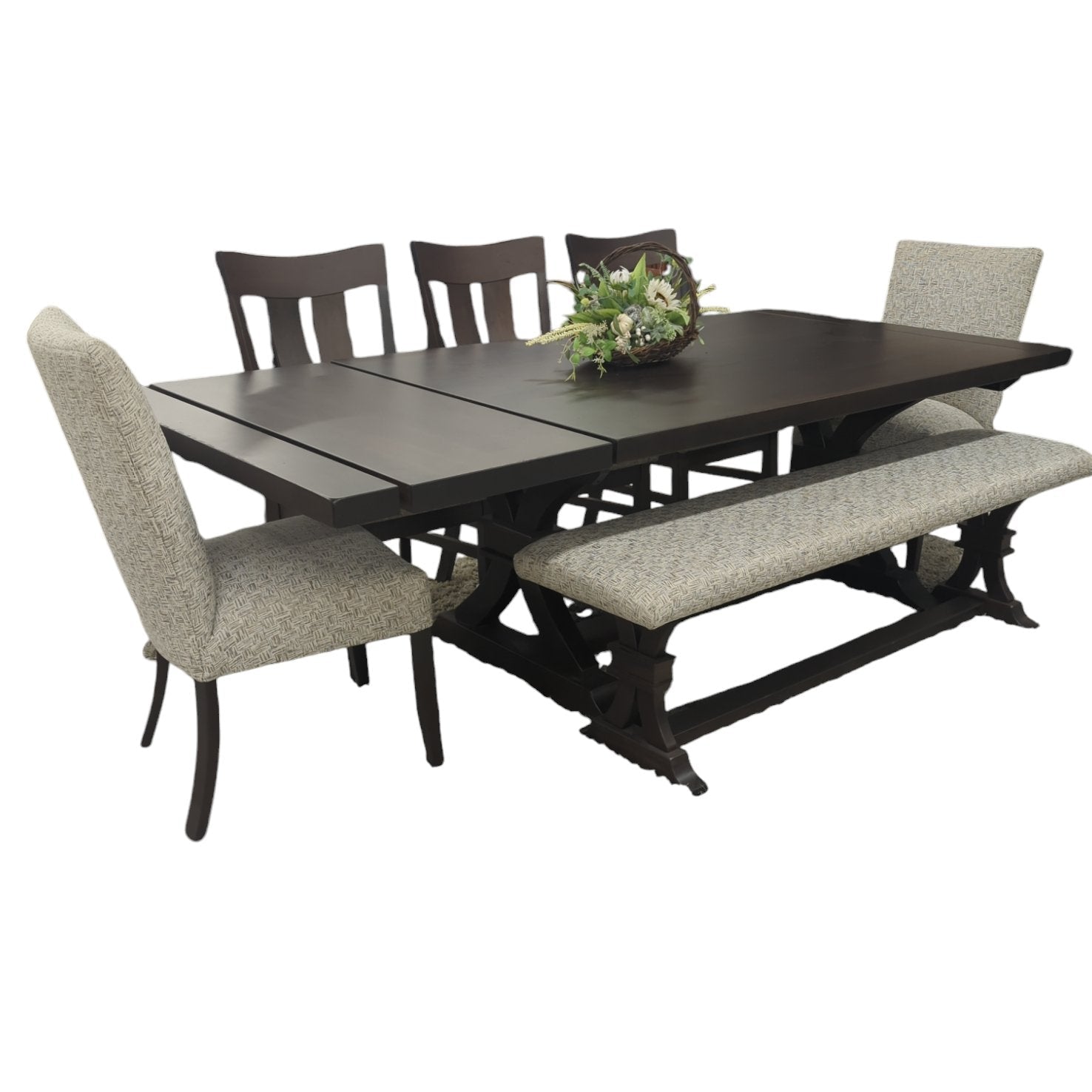 Dark brown trestle dining table with two panel back chairs, two upholstered side chairs and a matching bench, on white