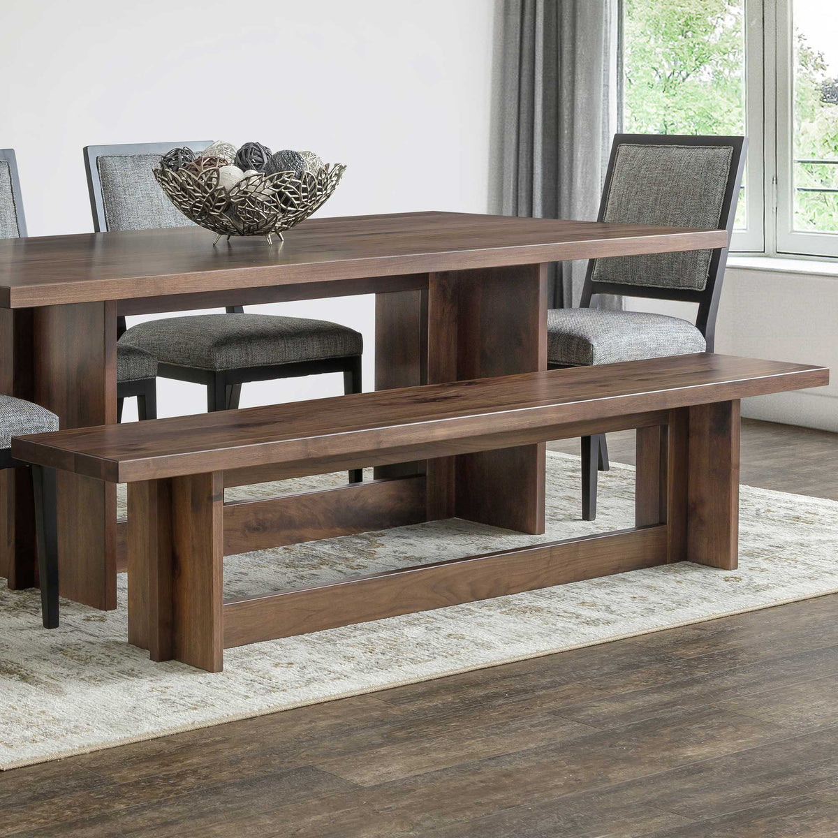 Walnut modern dining bench with plank seat and panel trestle base pulled alongside the matching dining table