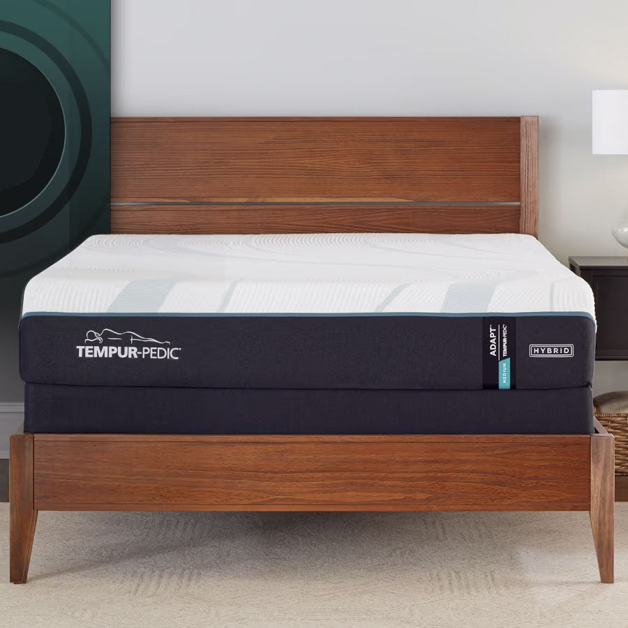 Medium feel hybrid foam mattress with a white cover and navy border on a walnut platform bed beside a lamp
