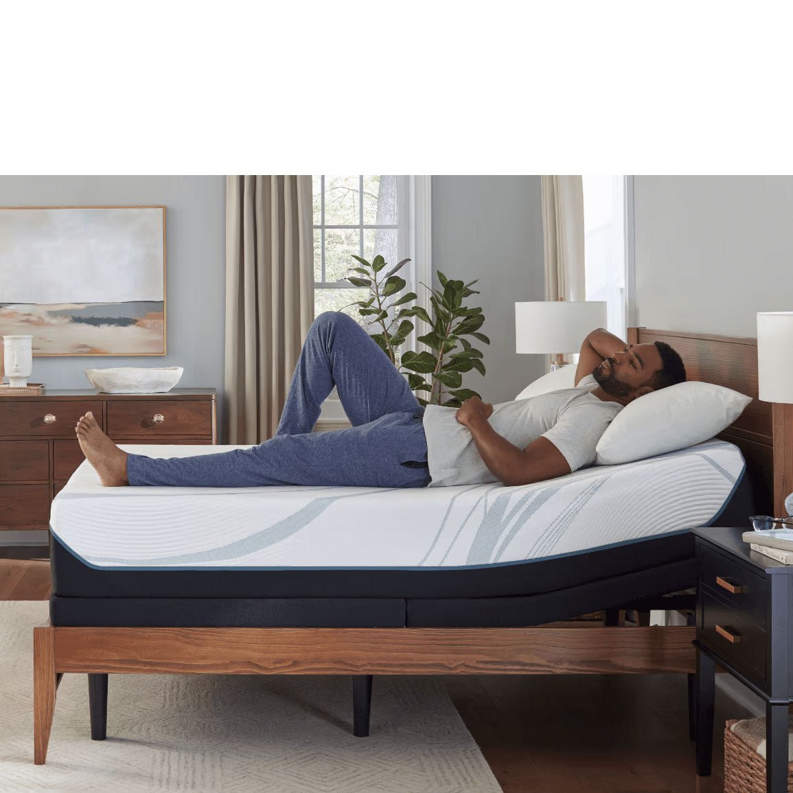Man reclining on an 11 inch foam mattress with the head raised on an adjustable base in a sunlit bedroom