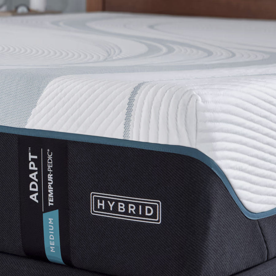 Close-up of the medium hybrid mattress corner showing the quilted white cover, teal piping and charcoal band