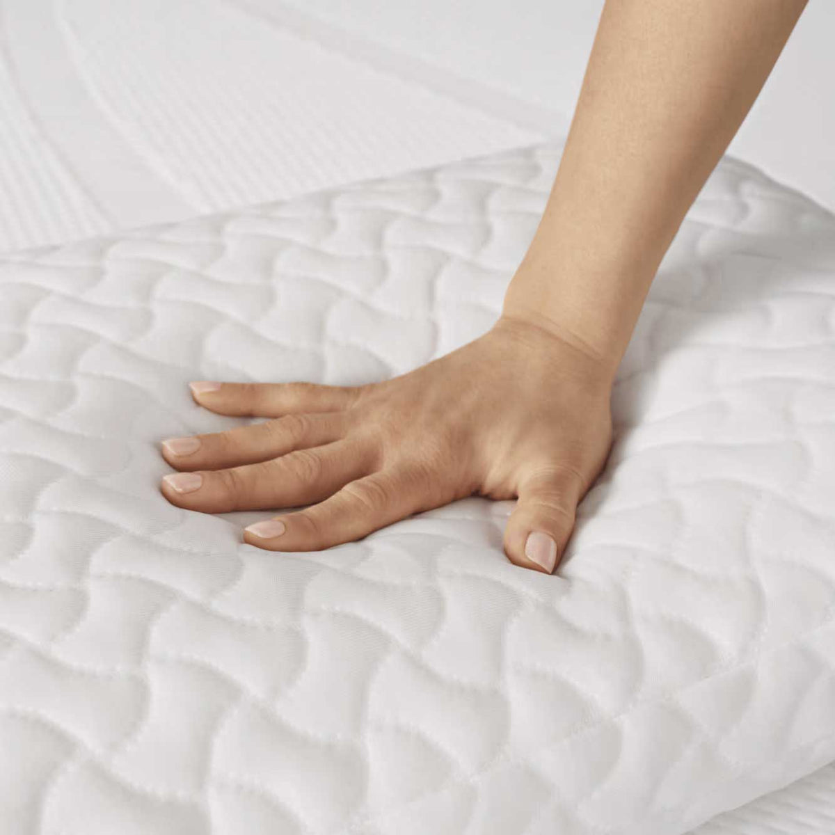 Hand pressing into the quilted pillow cover to show how the memory foam fill compresses and rebounds