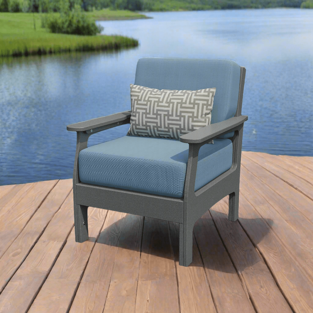 Gray poly patio club chair with blue deep-seat cushions and a patterned lumbar pillow on a wooden lakeside dock
