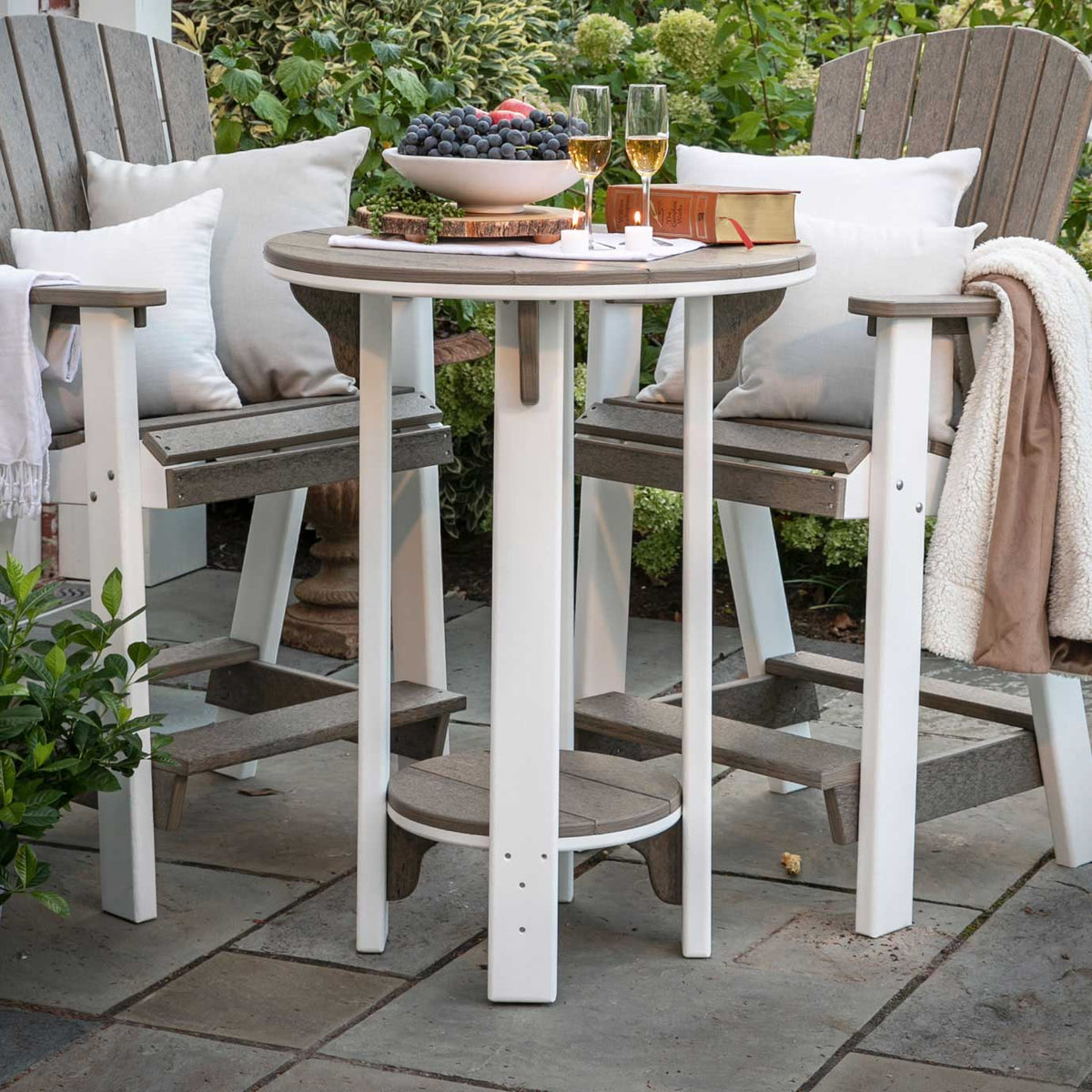 White and weatherwood bar height poly patio table with two tall Adirondack bar chairs on a garden patio