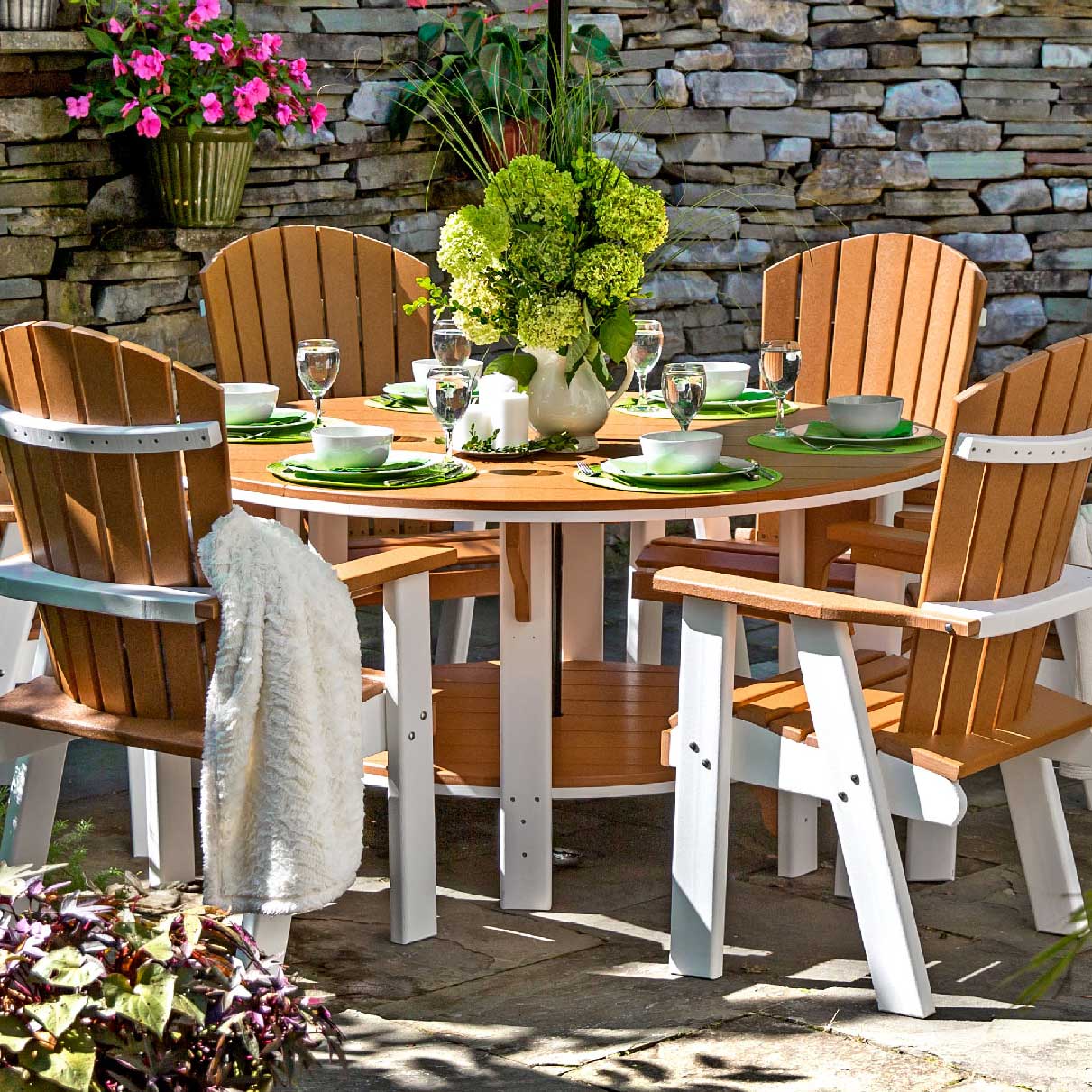 Cedar and white poly patio dining table with four Adirondack dining chairs and hydrangeas by a stone wall