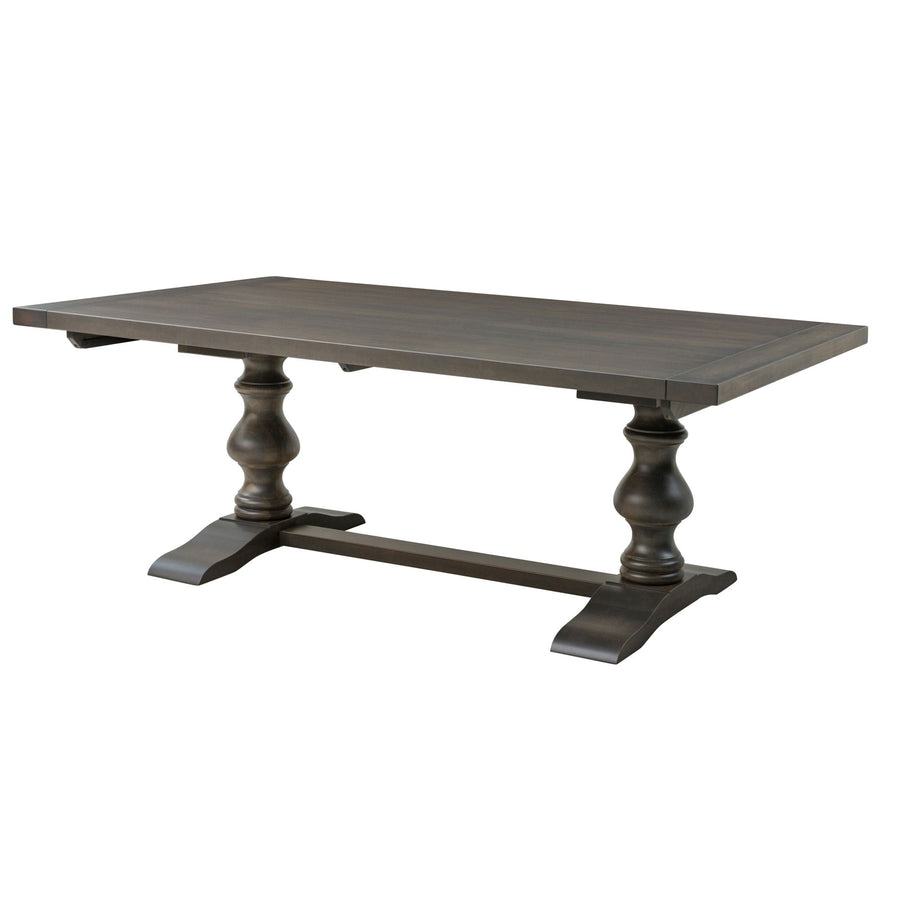 Expandable rectangular pedestal dining table in a weathered gray finish with two turned pedestals and a curved trestle base