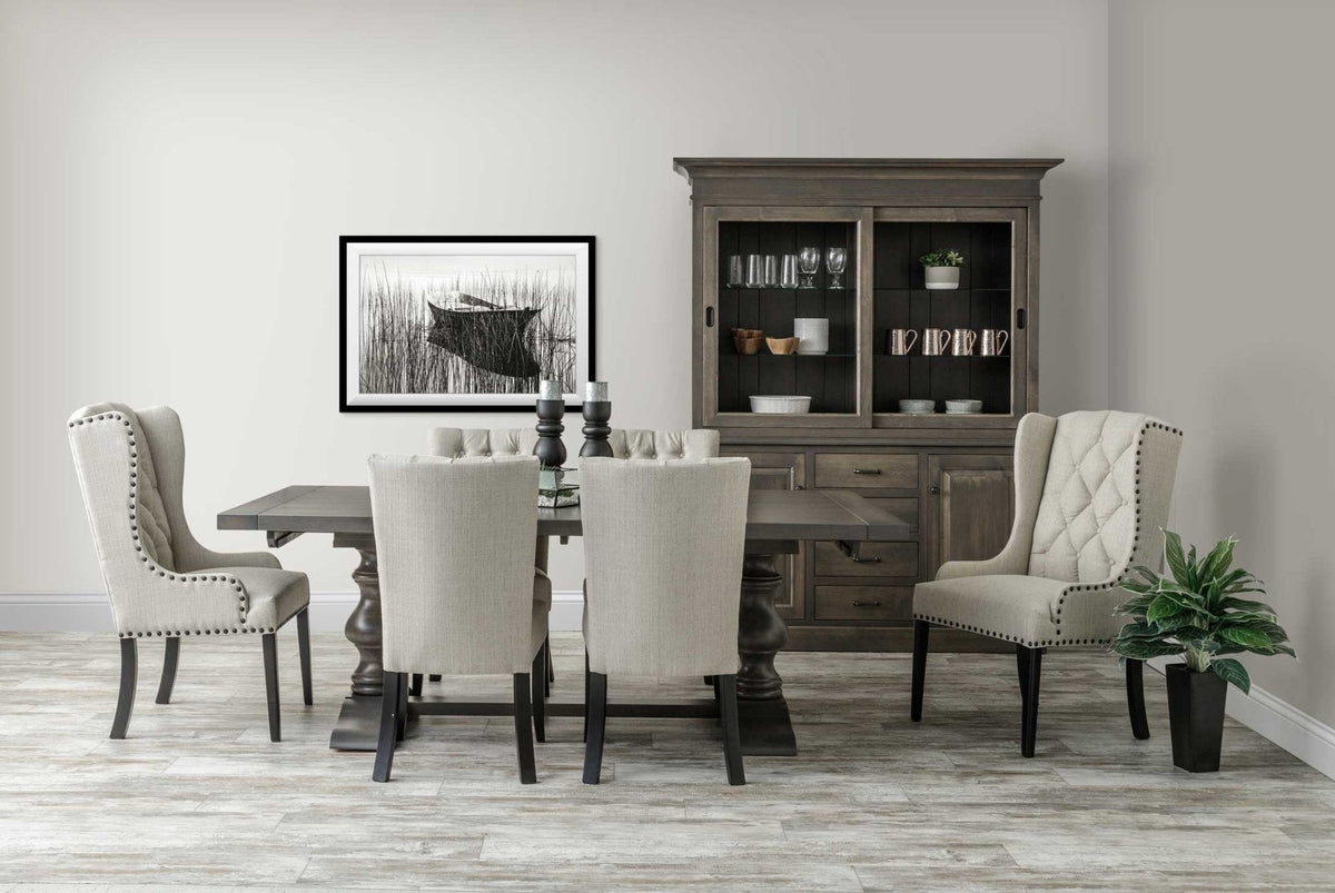 Wide view of a gray pedestal dining table with six upholstered linen chairs and a matching china cabinet