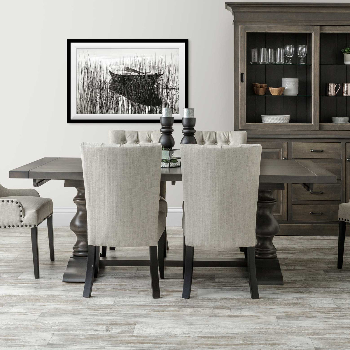 Gray stained double pedestal dining table with upholstered linen chairs and a matching china cabinet in a soft gray dining room