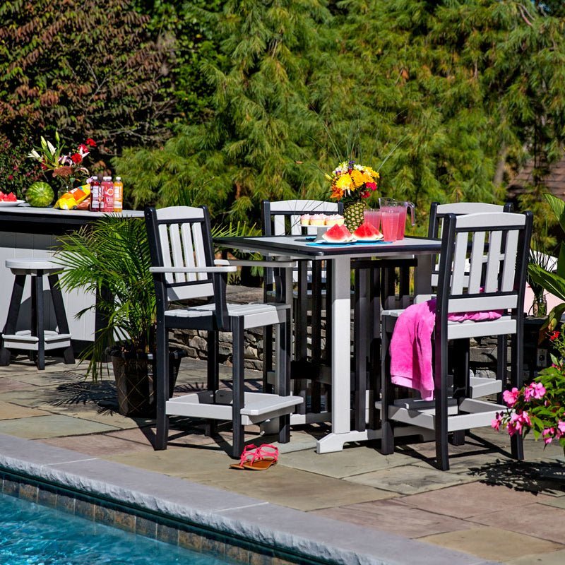 Black and white poly square bar height table with four tall slat back chairs beside a swimming pool