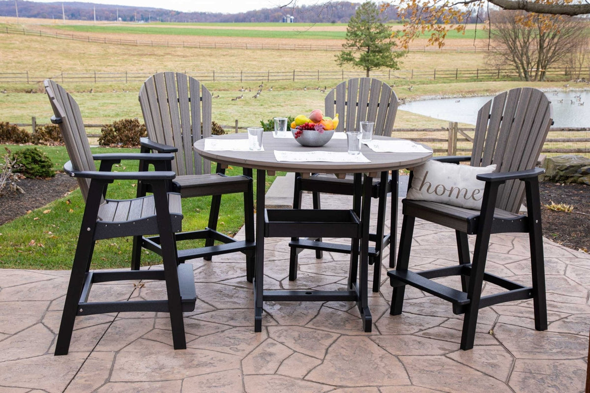 Gray and black poly bar height patio set with a round 54 inch table and four tall fan-back bar chairs on a stamped patio