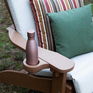 Cedar toned Adirondack chair arm with an inset cup holder holding a bottle beside striped pillows