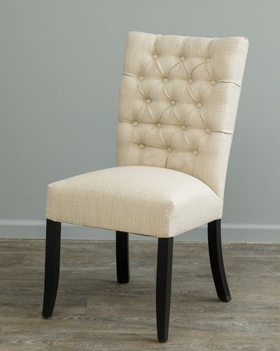 Cream linen dining side chair with button tufted back, wide padded seat and black tapered legs against a gray wall