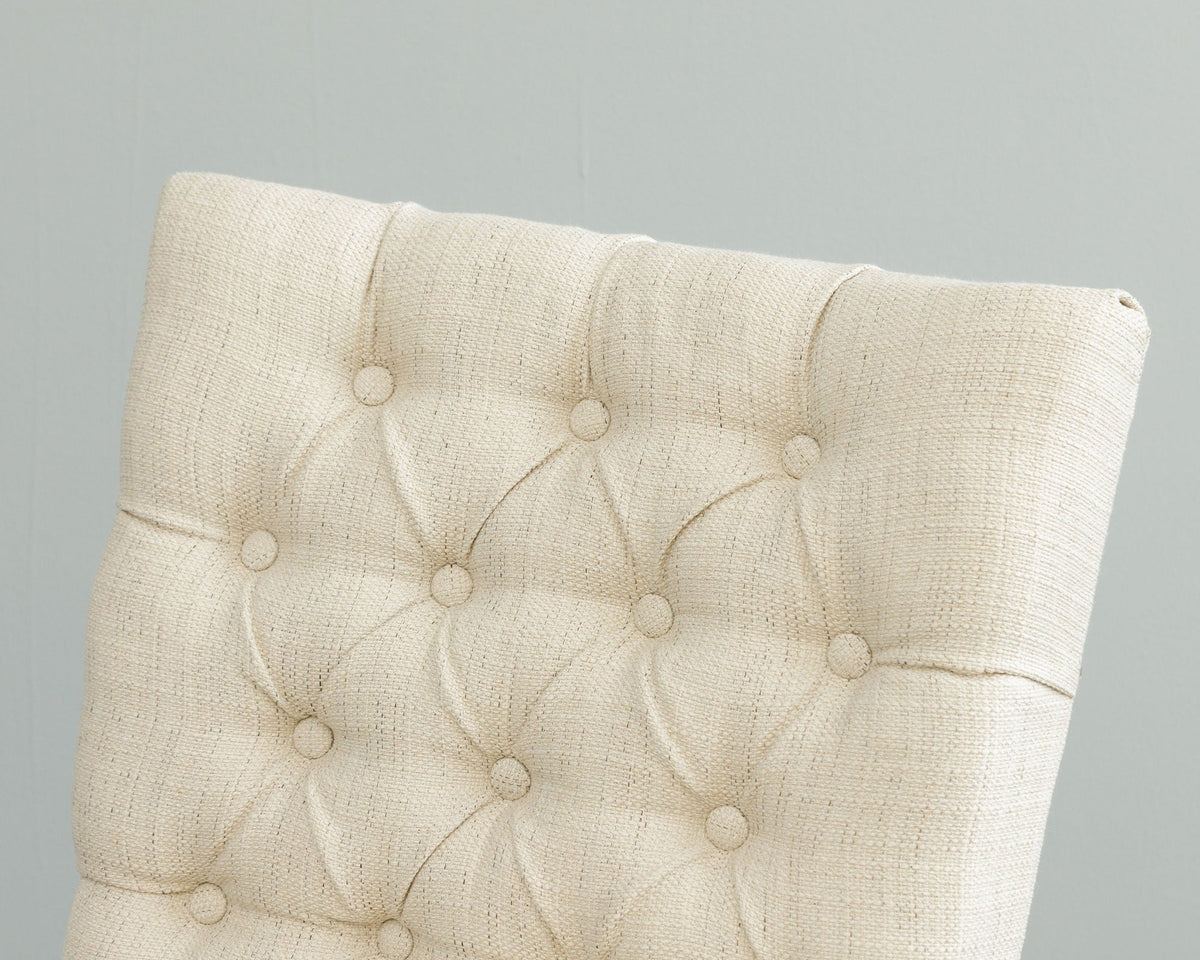 Close view of the button tufted cream linen chair back showing the woven fabric texture and matching fabric buttons