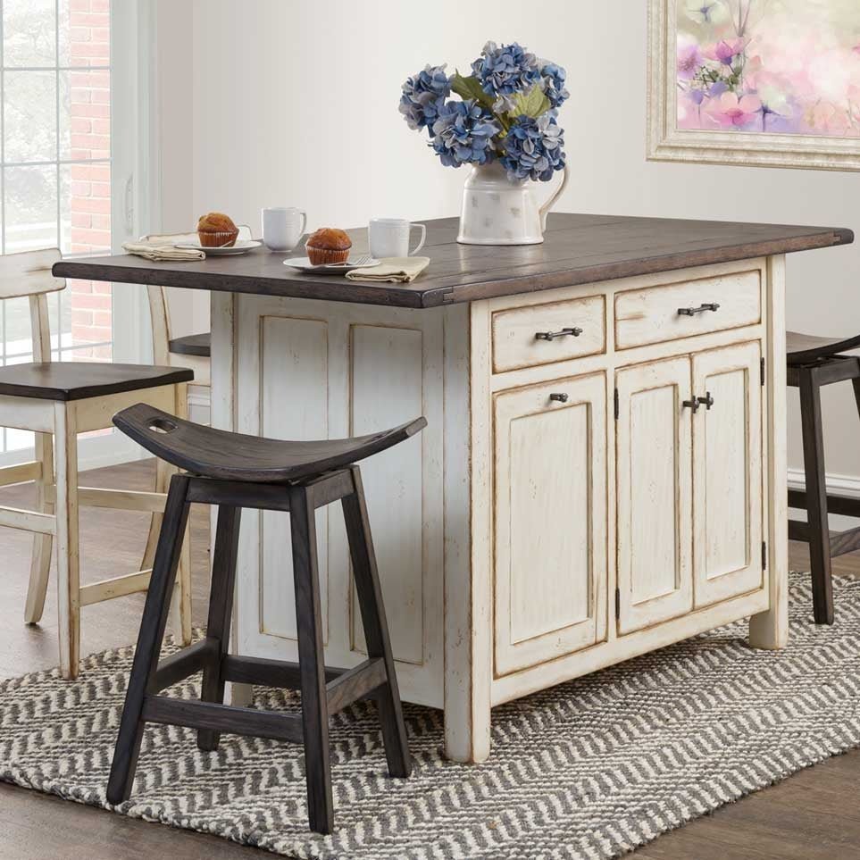Antique white kitchen island with dark plank top, two drawers, three doors and black saddle stools on a striped rug