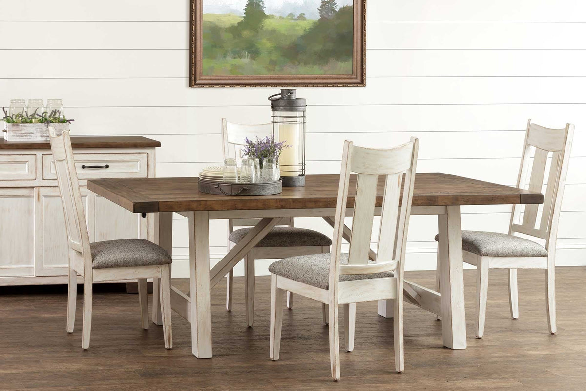 Two-tone trestle dining set with brown plank top, four whitewashed chairs and a sideboard in a shiplap room