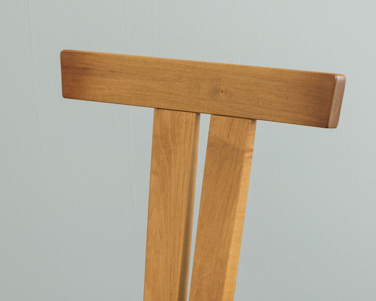 Close-up of the T-shaped crest rail and twin back splats on a cherry Astoria mid century dining chair