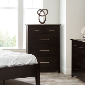 Espresso five drawer chest of drawers with silver bar pulls beside a bed and matching dresser by tall windows
