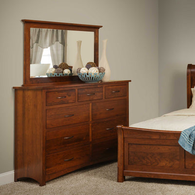 Cherry nine drawer high dresser with a wide mirror styled with vases and decorative balls beside a sleigh bed