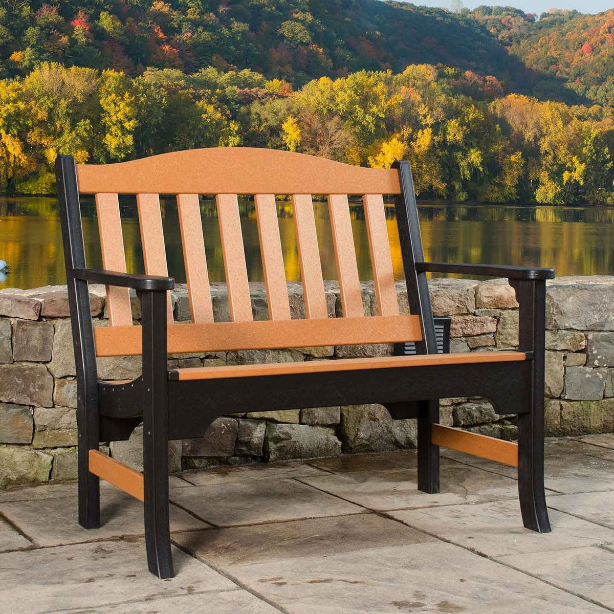 Two tone cedar and black poly garden bench with arched slat back on a stone patio above a lake