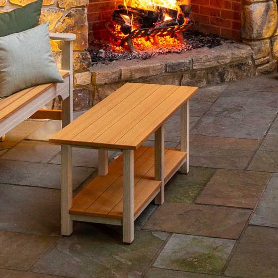 Two tone brown and ivory poly patio coffee table with a lower slat shelf on a stamped concrete patio