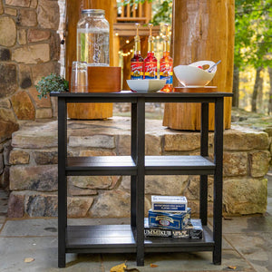 Black poly outdoor buffet console table with two open shelves, holding drink dispensers and games