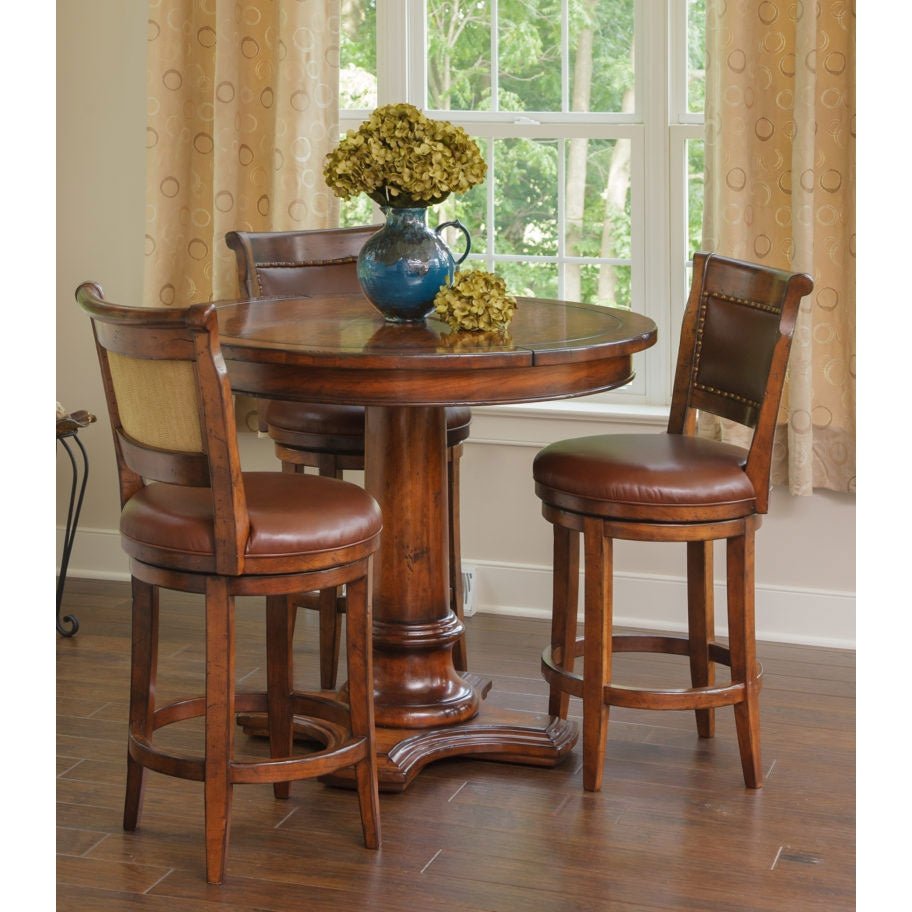 Round cherry pub table with three brown leather swivel bar stools in a sunny bay window nook