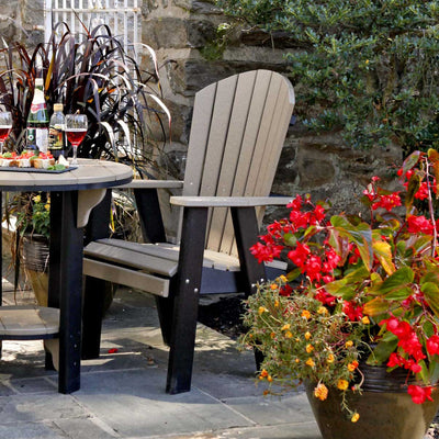 Weatherwood and black poly bistro dining chair with a fanned slat back pulled up to a round patio table