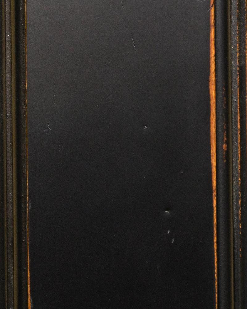 Black Heritage paint sample on a beaded panel with worn edges revealing warm orange wood underneath