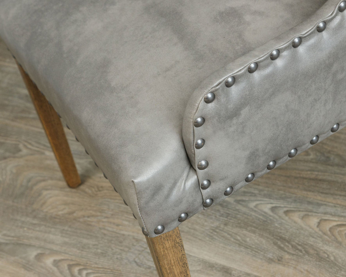 Close view of the gray leather seat corner and rolled arm outlined with pewter nailhead studs